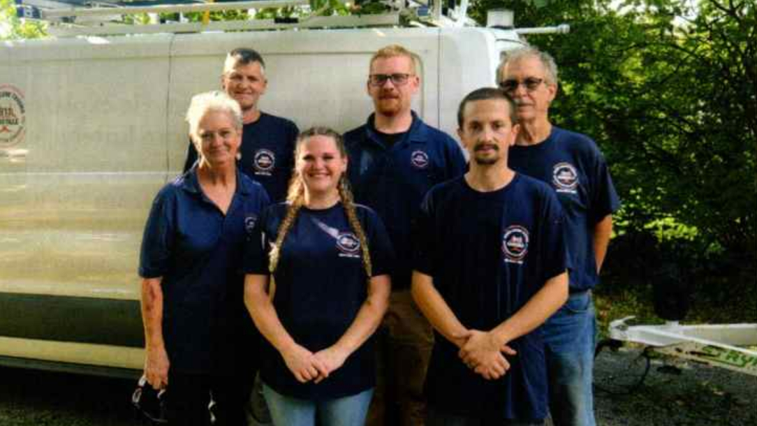 911 Knoxville Decon professional response team standing in front of their service van, wearing matching company navy blue uniforms.